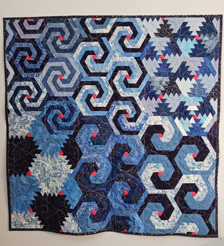 Spirals change shape across the face of the quilt.